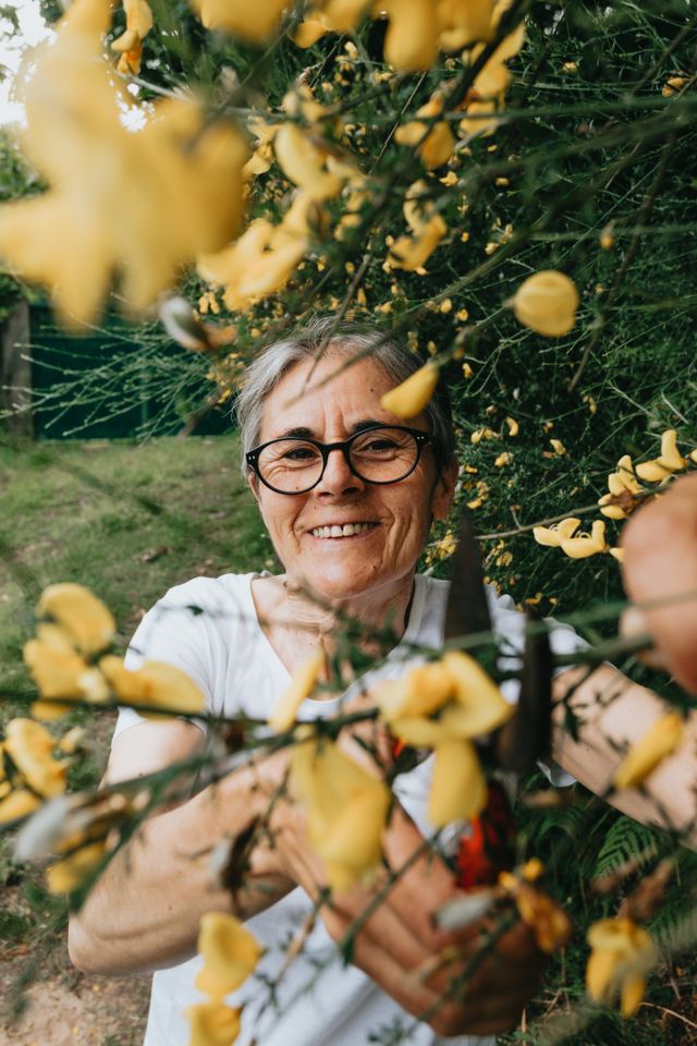 A lady smiles at you through a bush of yellow flowers